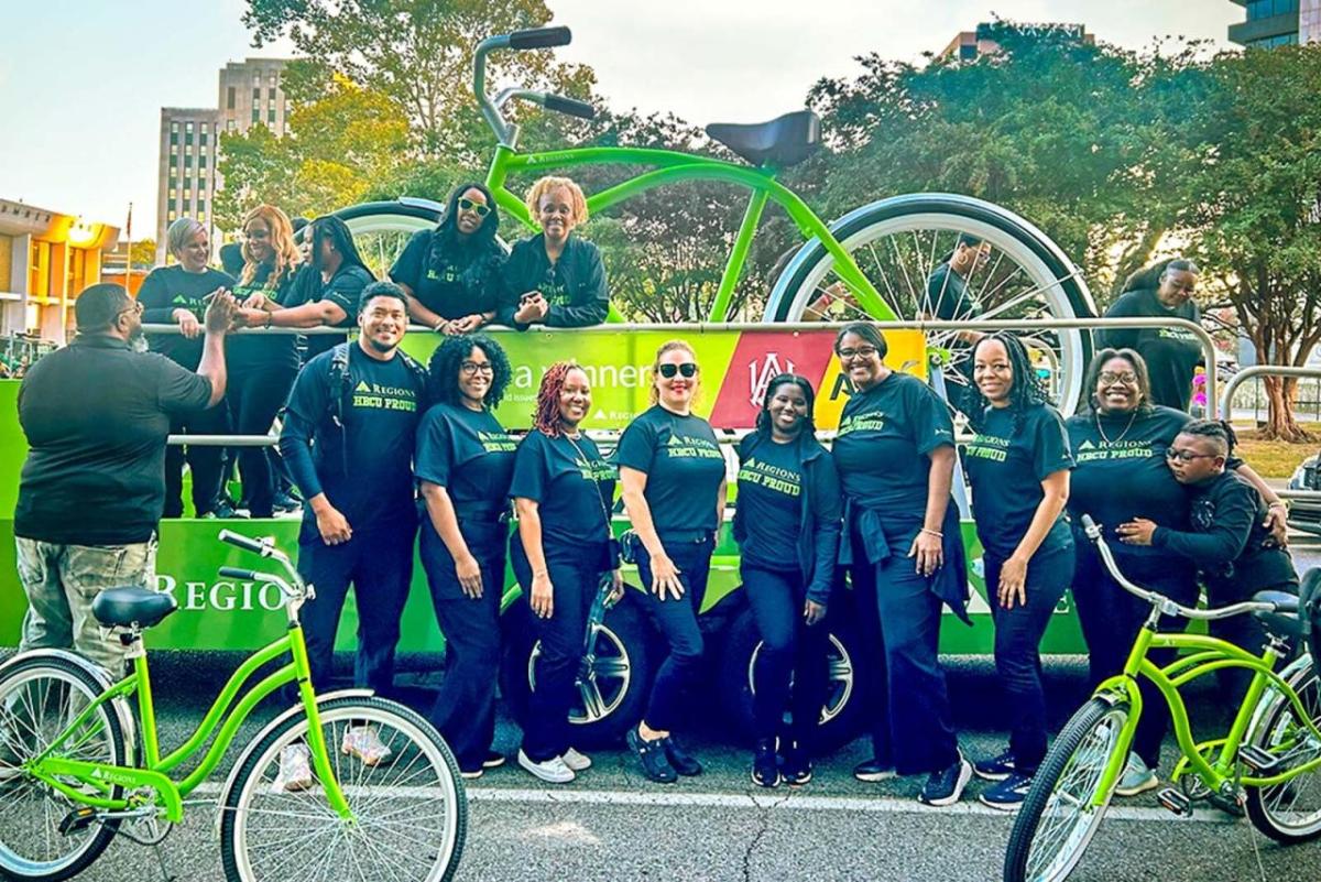 Volunteers posed in front of a float with a giant green bike. Other, normal sized, green bikes in front of them.