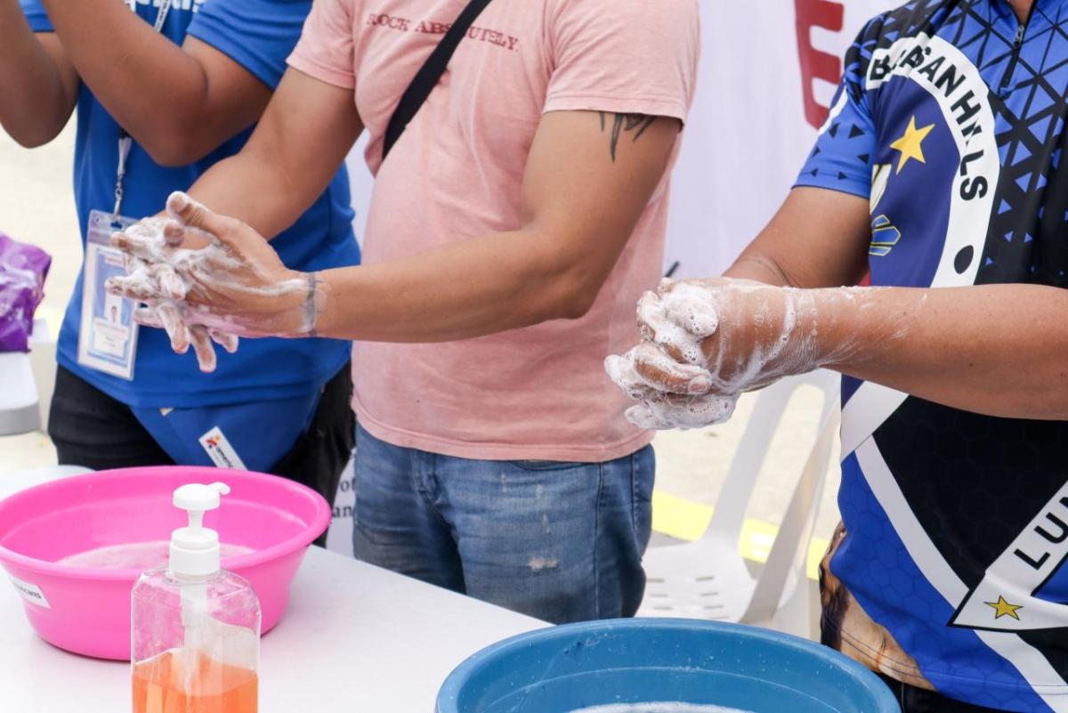 people cleaning hands in small basins