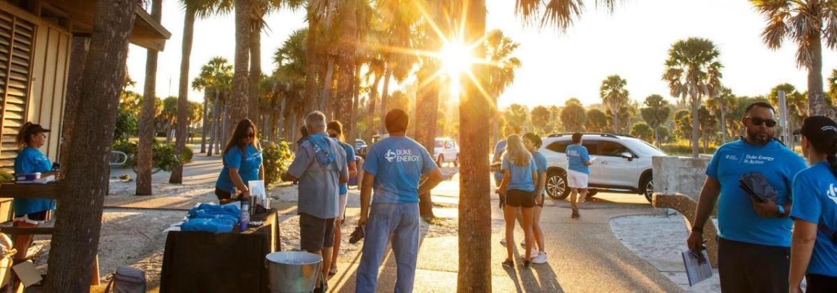 A group of volunteers gathered on a sidewalk in a park setting.