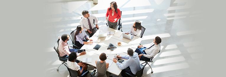 employees sit around a square table in a white room