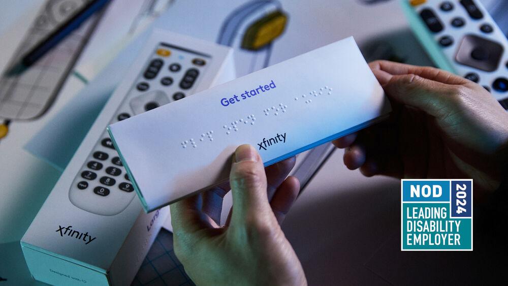 Two hands holding a packet that says "Get started" and has braille translated underneath. An xfinity remote beneath on a table.