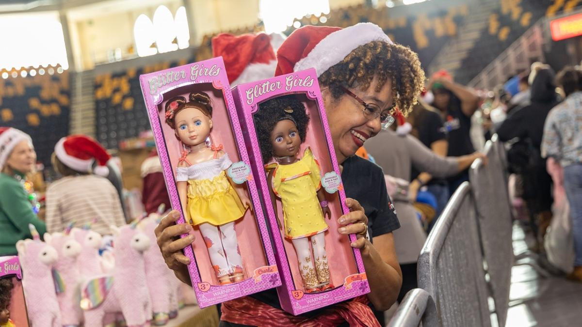 A volunteer holding up two packaged dolls