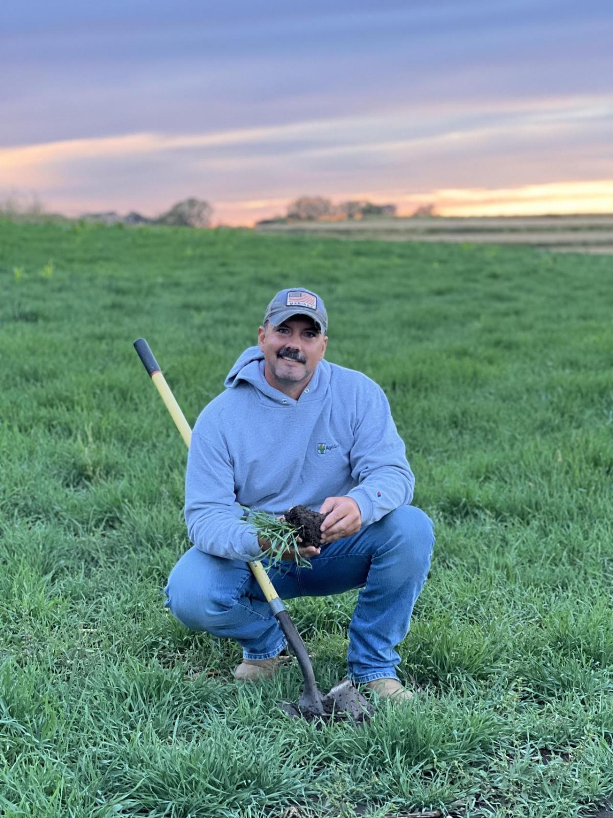 A person crouched in a field of grass.