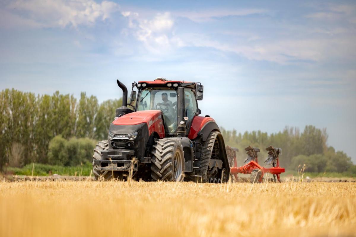 A person in a farming machine, tilling the soil in a field.