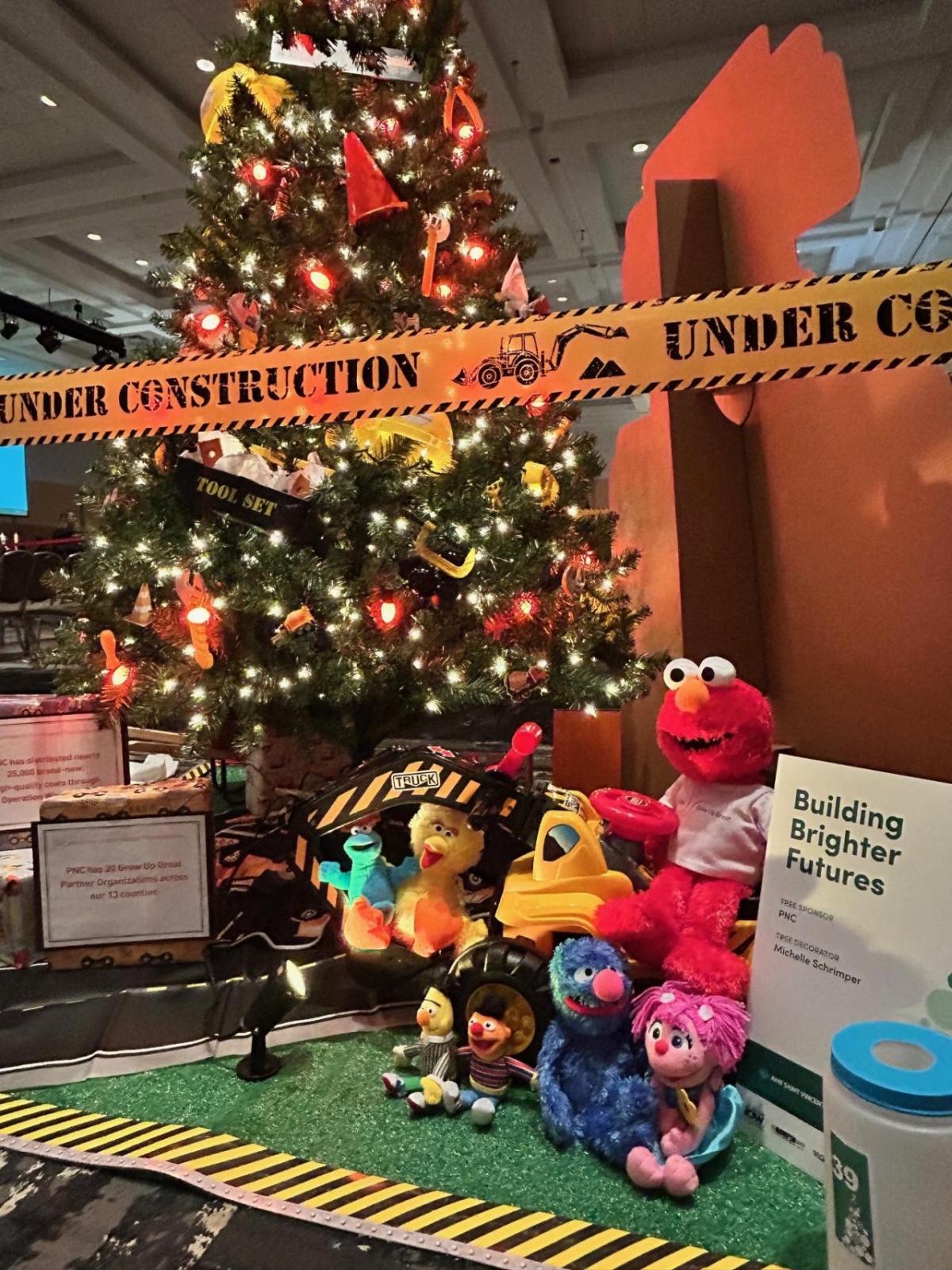 A decorated christmas tree with a display of toys in front.