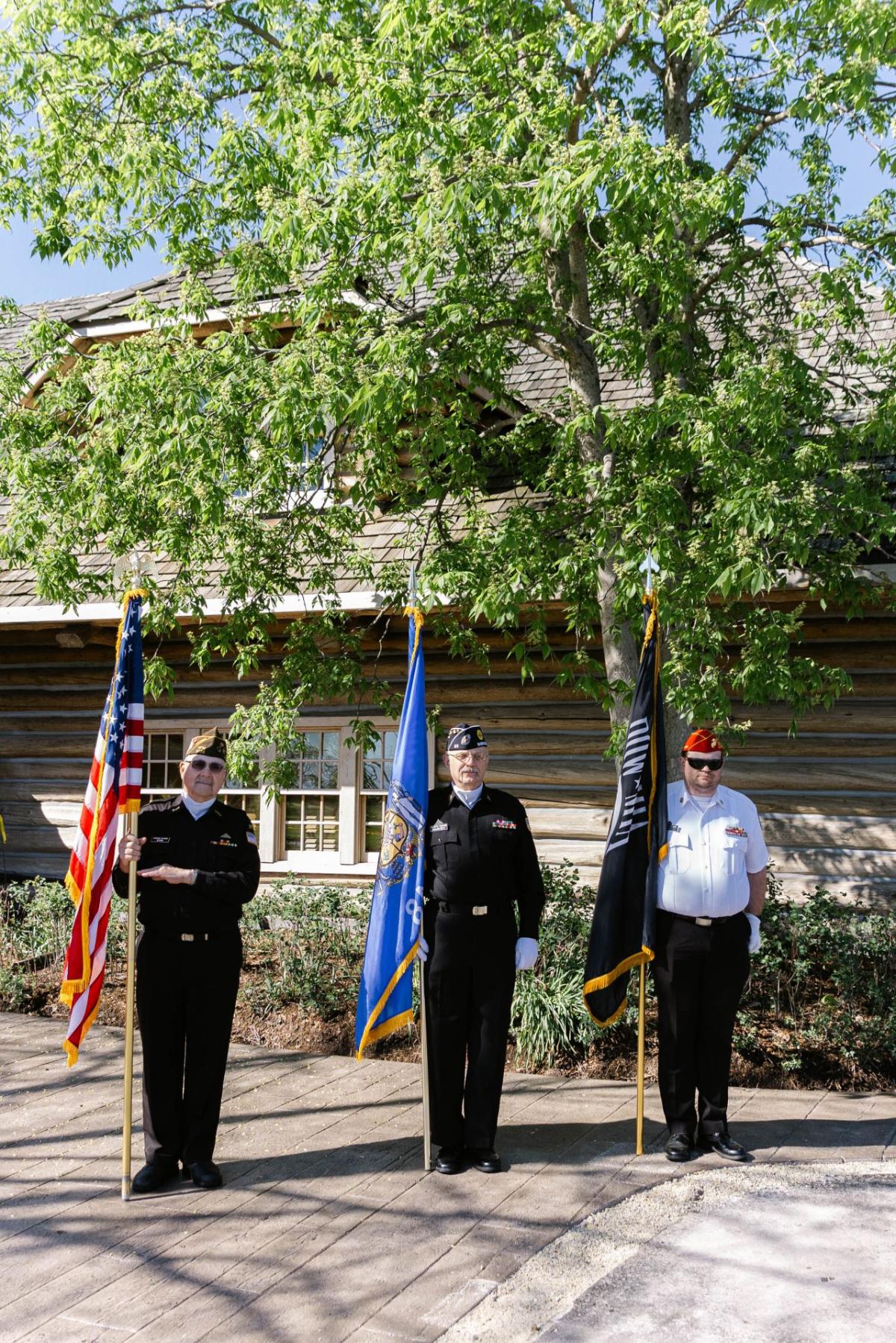 Three people in uniform holding flags to their side.