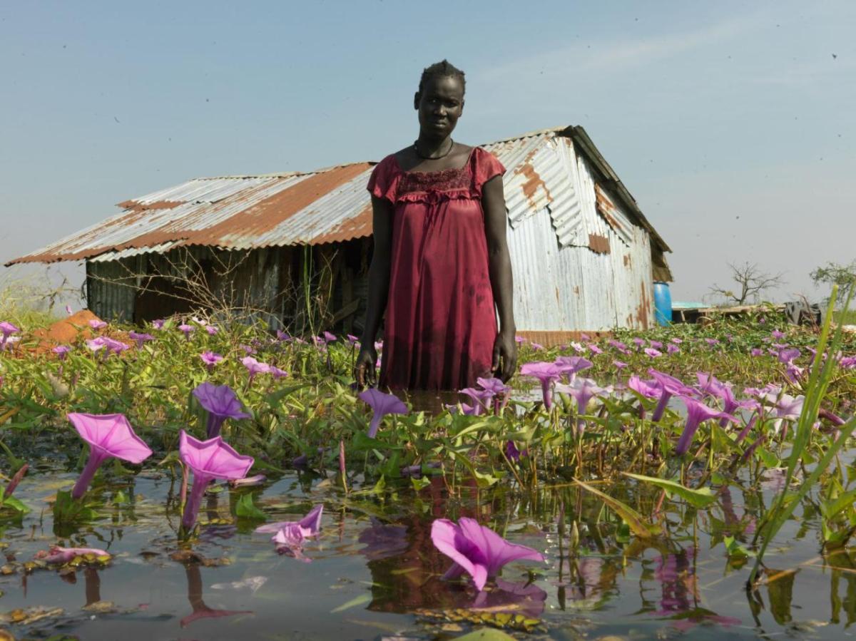 Portrait of Nya Jol outside her flooded home. "My husband goes to market often to find work, while I remain here to look after the children. I hope he finds some casual work soon so we can buy vegetables to eat with the fish we catch" says Nya.