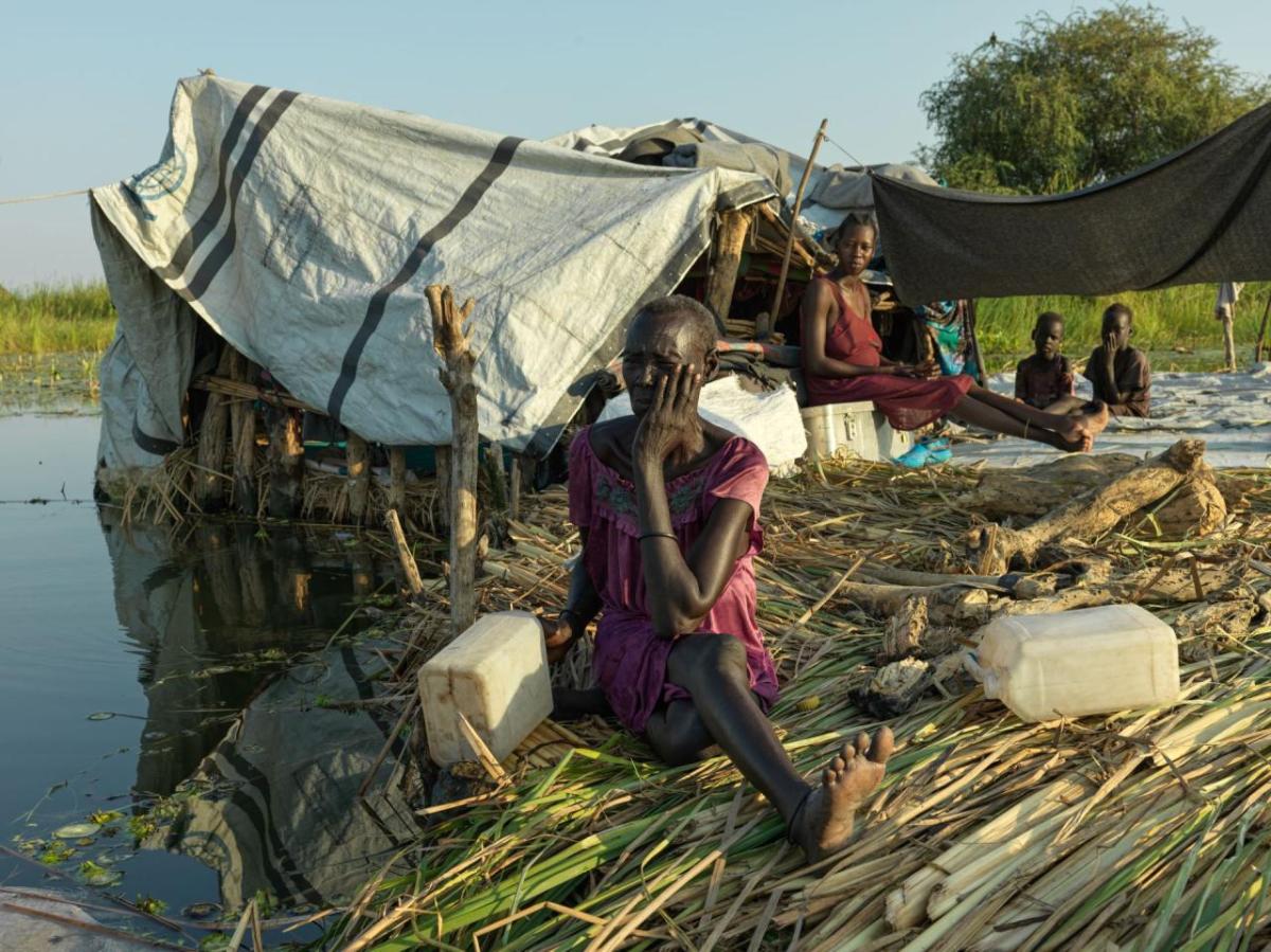 A family sit on their floating pontoon made from tightly packed grass.