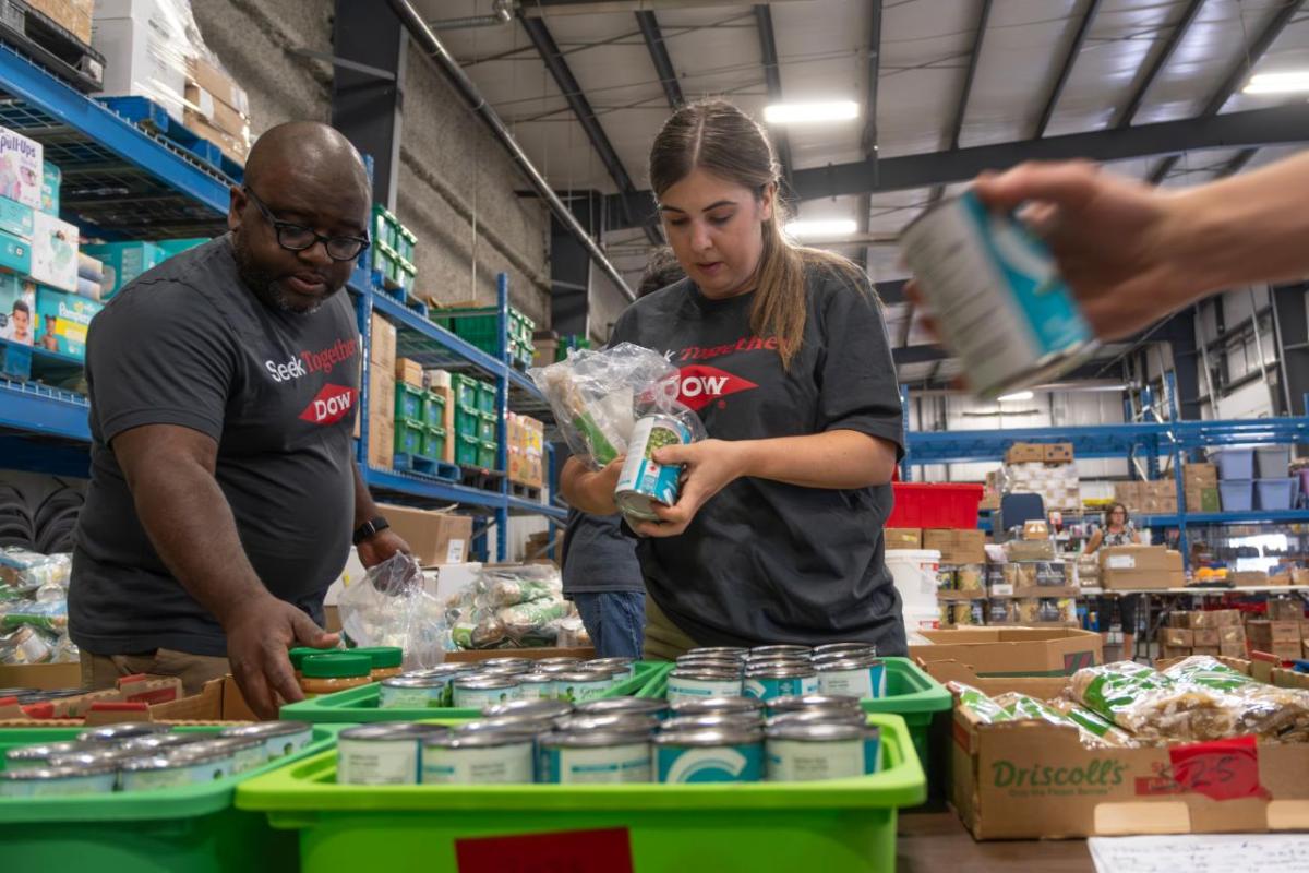 Volunteers sorting cans of food in a warehouse setting.