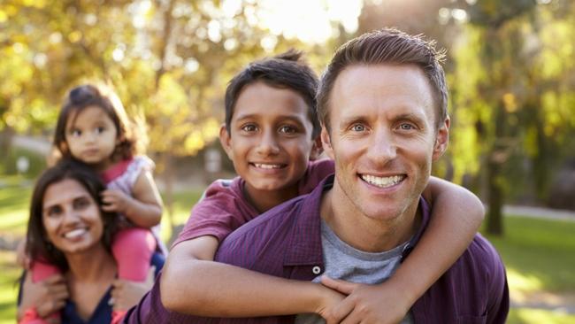 Two smiling adults, each carrying a child on their back