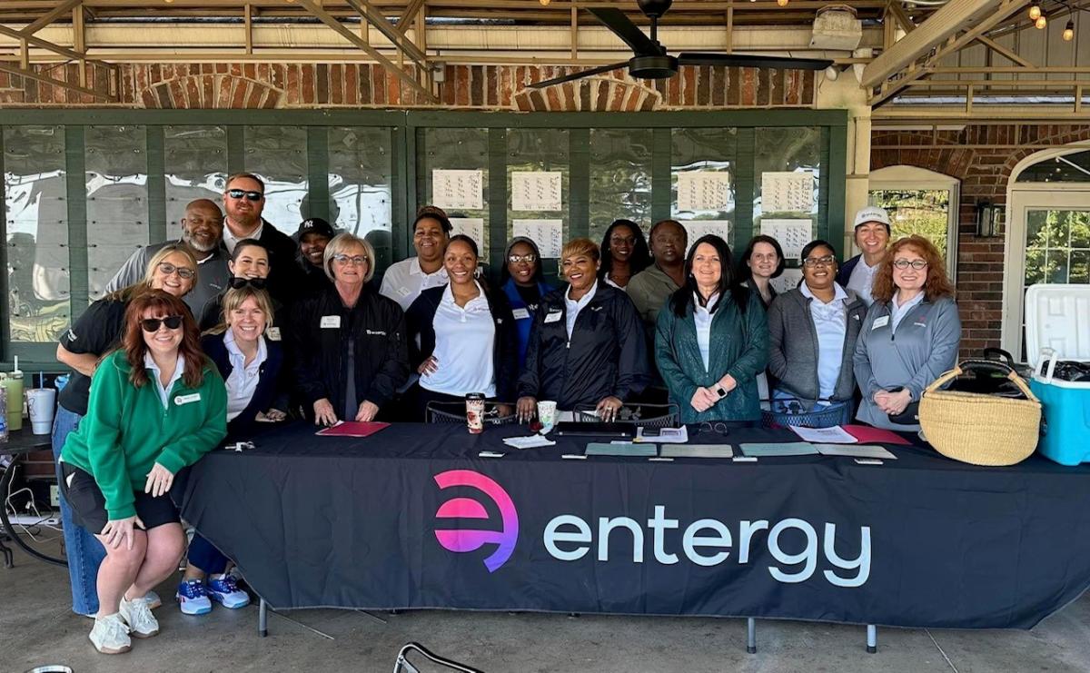 A group posed behind a table with "entergy" logo on the front.