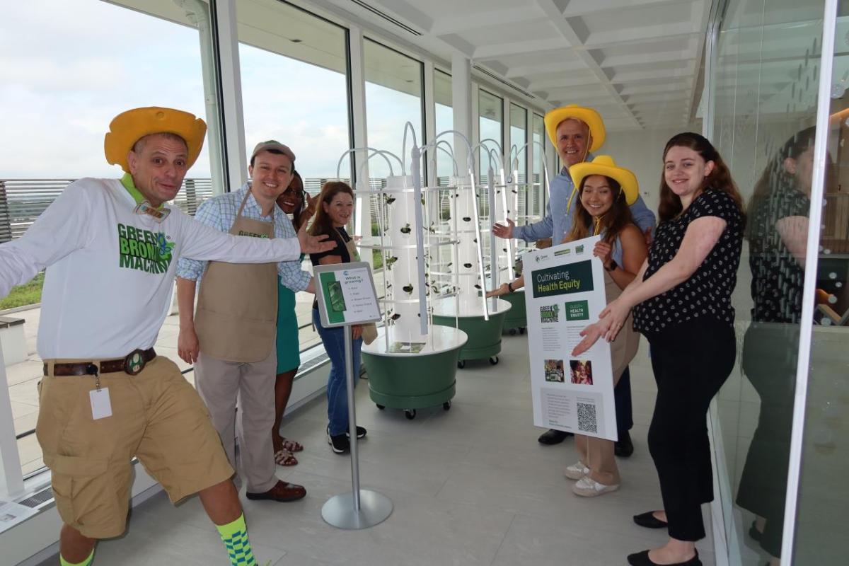 Employees and volunteers showing off the tower planters in a hallway