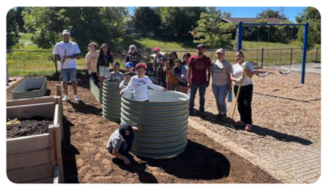 Adults and kids working on a playground/garden area.