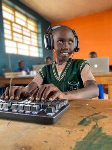 A smiling child with headphones using a computer.