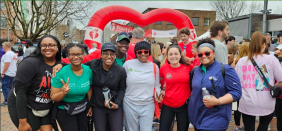 A group posed outside, a heart shaped balloon in the background.