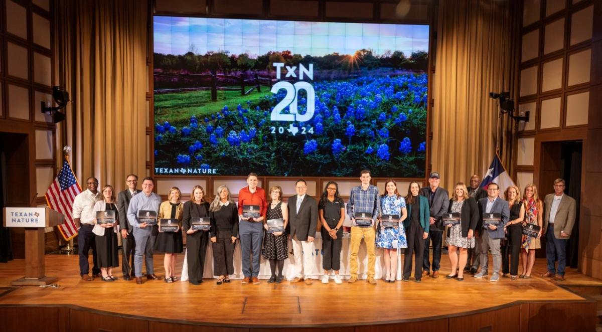 A group of honorees posed on stage with awards.