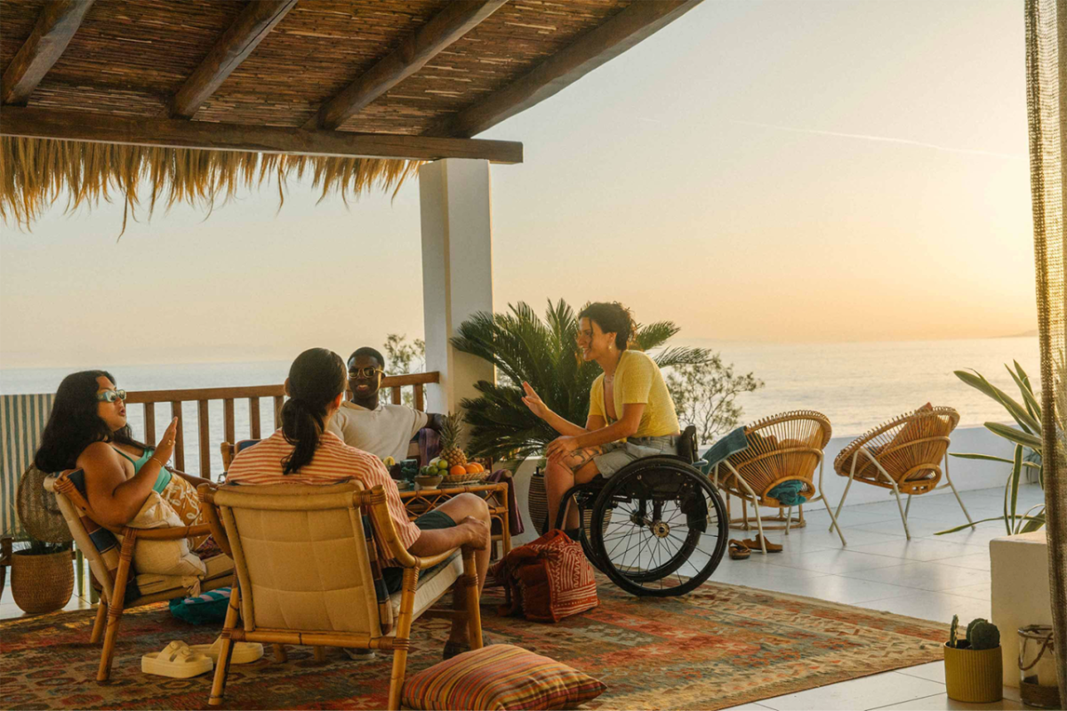 A group seated in a covered area overlooking an ocean expanse.