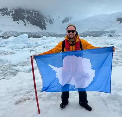 Josh Hasdell holding an Antarctica flag.