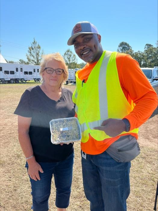 Two people posed with a container of food