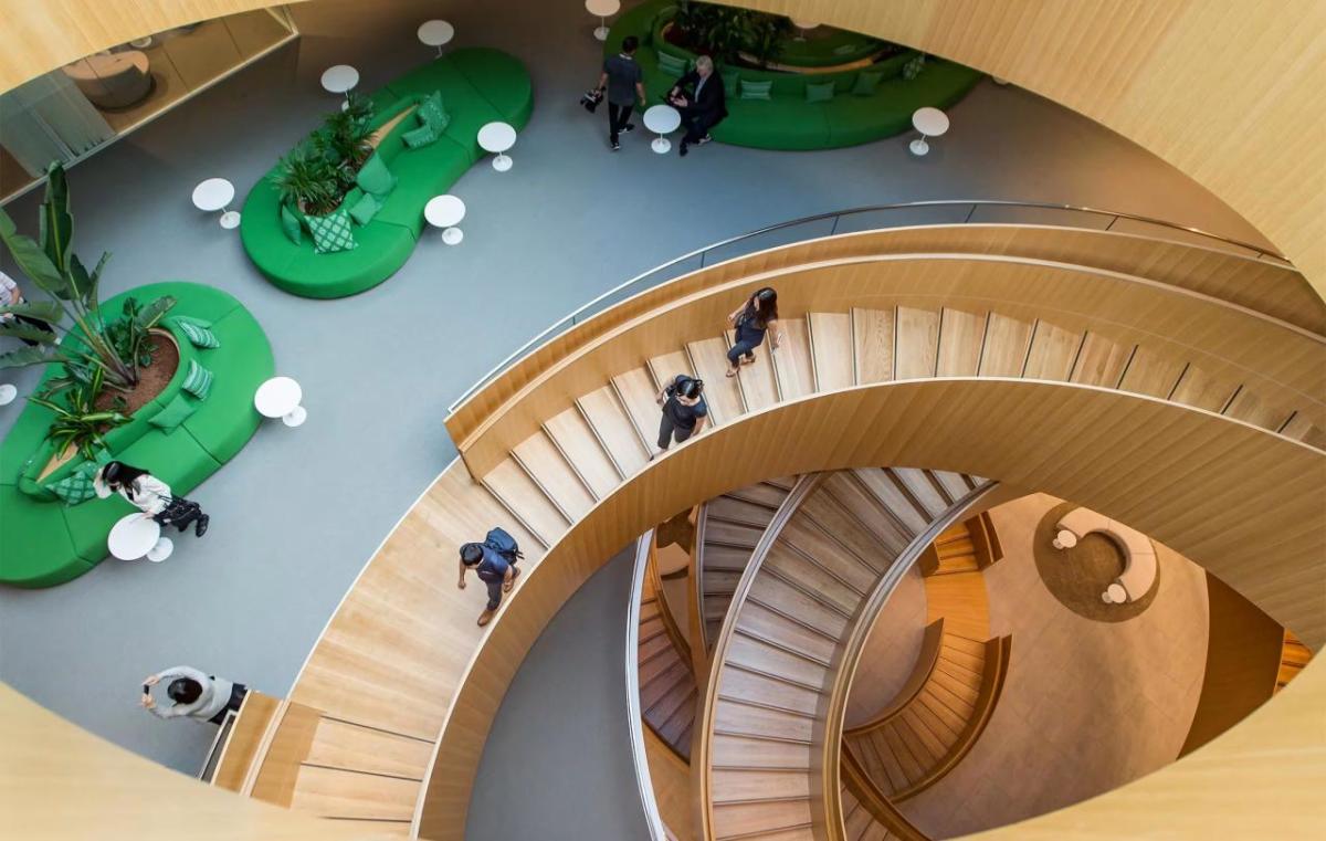 Interior of a spiral wooden staircase and seating areas at different levels.