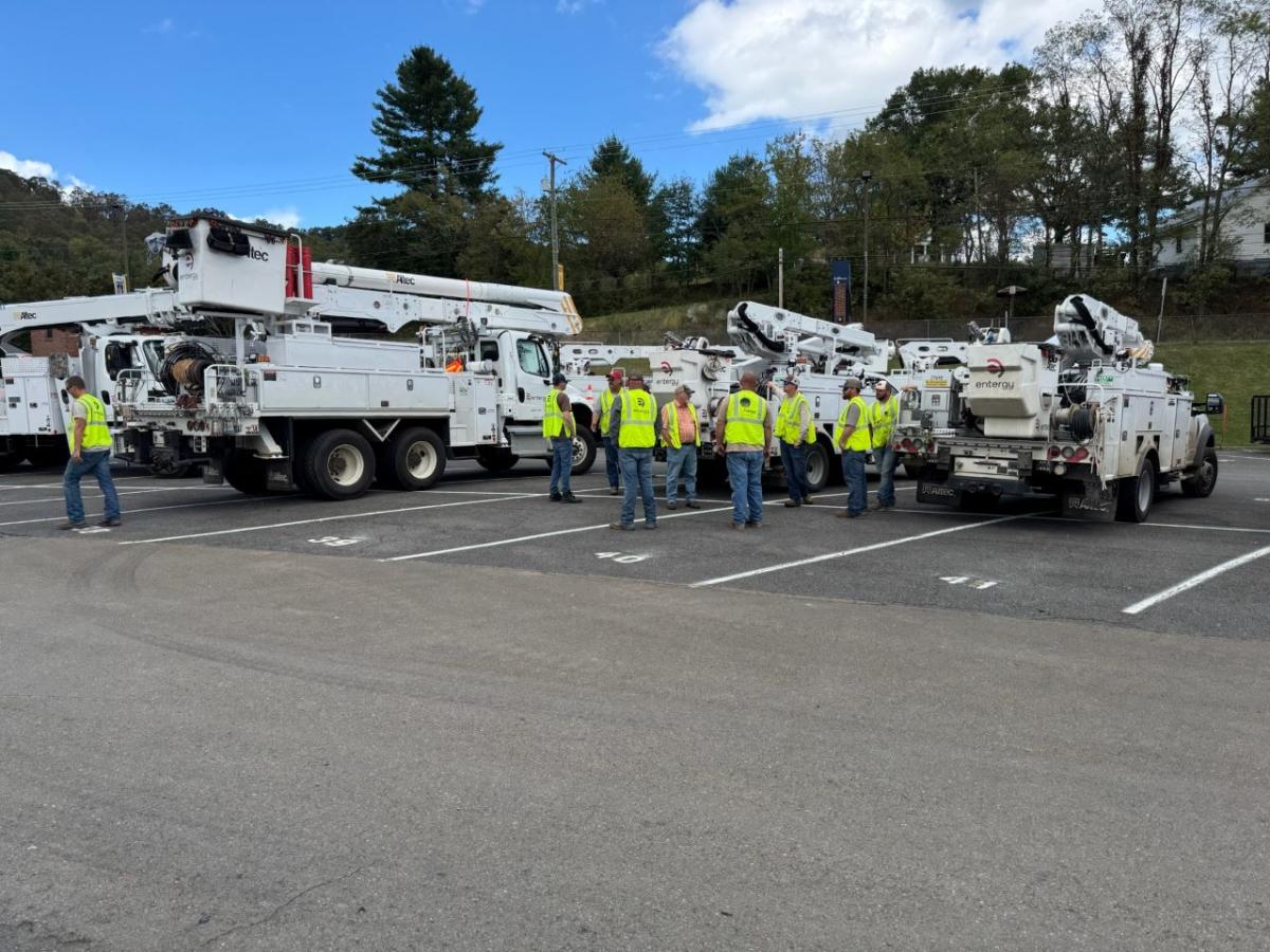 Employees in high-vis vests gathered next to parked bucket trucks.