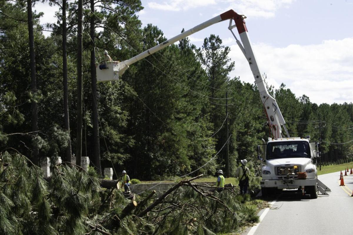 Line workers, one in a bucket-lift, repairing down power lines.