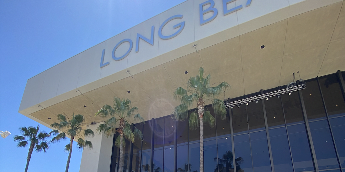 The outside of a 'Long Beach' building that has palm trees outside the windows 