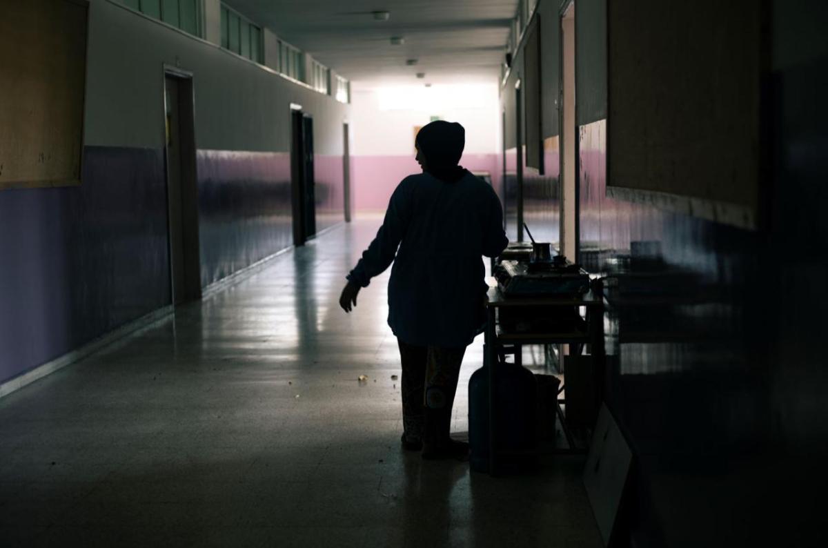 A woman cooks in one of the corridors of the Supplementary School for Girls in Tyre, Lebanon, where hundreds of people displaced by the armed conflict in southern Lebanon are sheltering. 