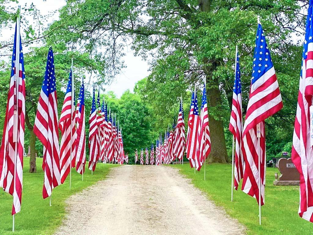 American flags line both sides of a dirt path.