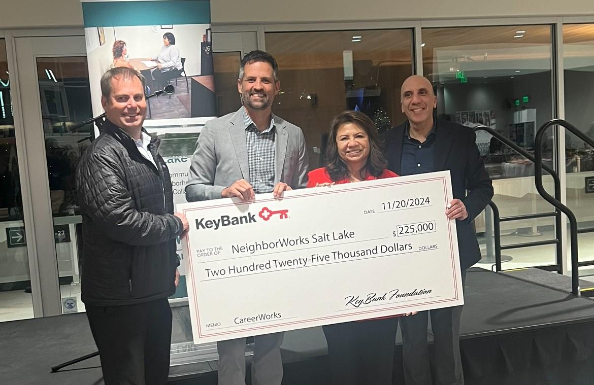 Four people holding an oversized check and smiling