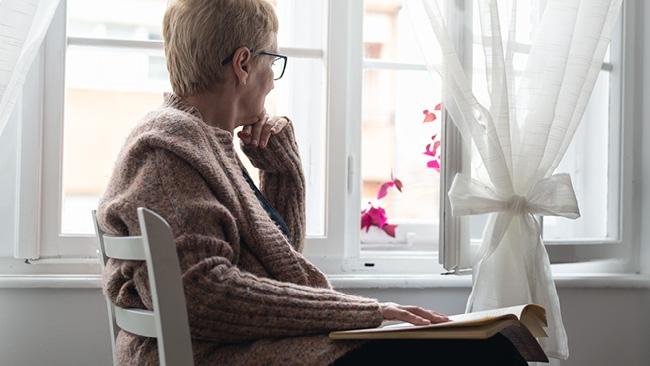 A person gazing out a window with a book on their lap