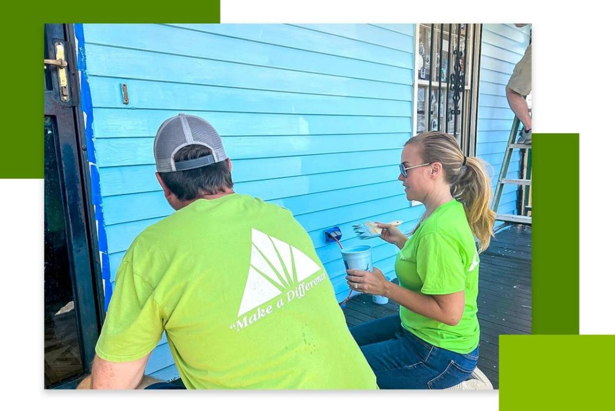 Volunteers painting the exterior of a home blue.