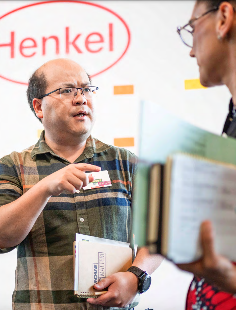Henkel employees talking, carrying paperwork