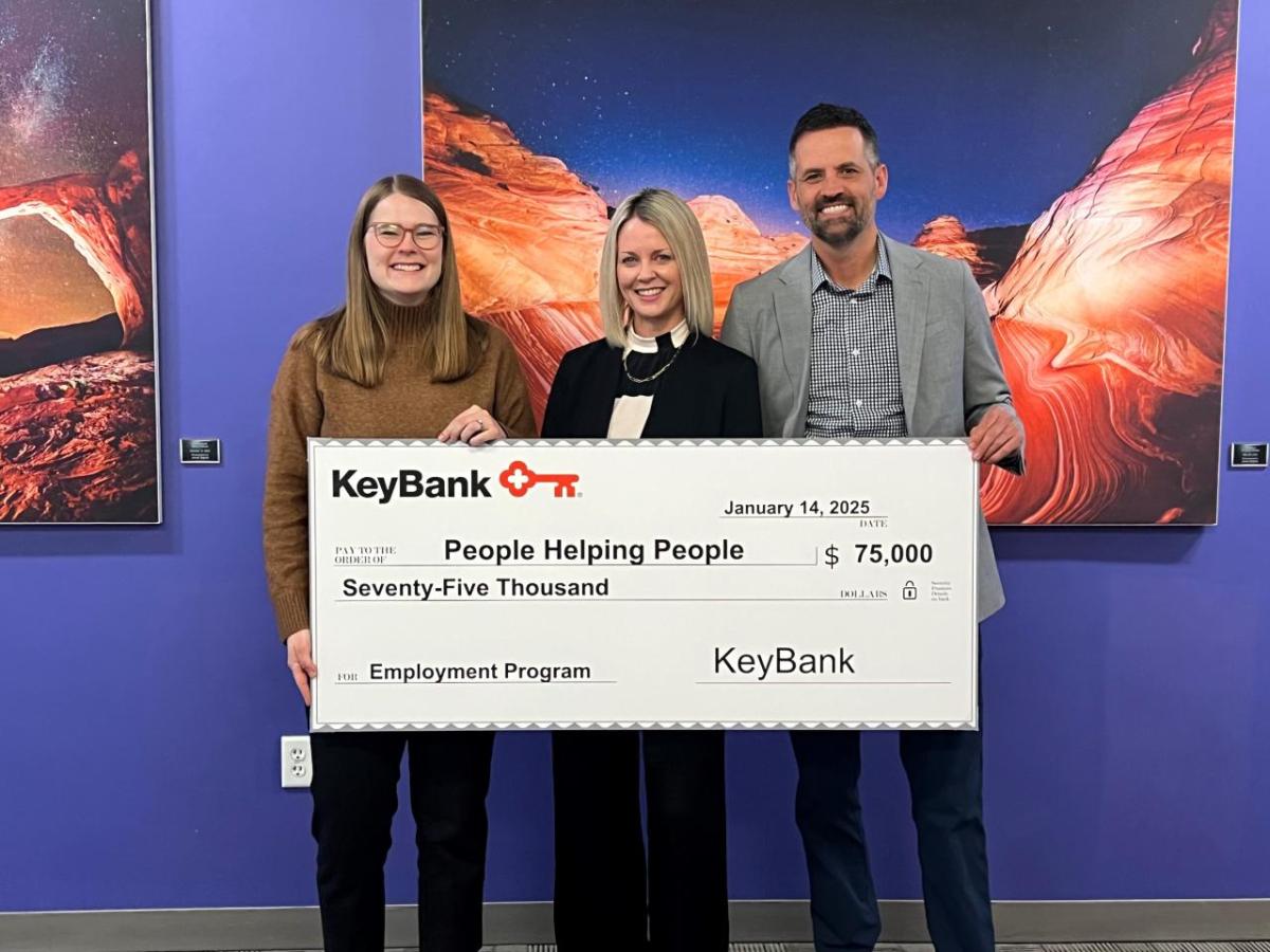 Three people holding an oversized check from KeyBank