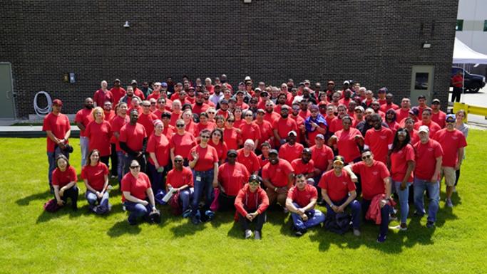 A large group posed outside in matching orange shirts.