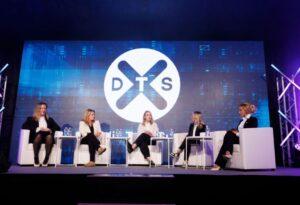 Five people seated on a stage. DTS logo displayed behind them.