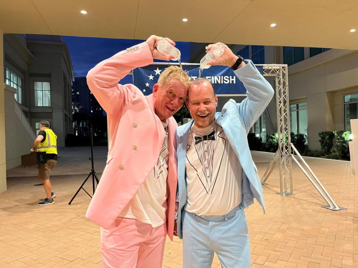 two men in pastel tuxedos pouring water on their heads