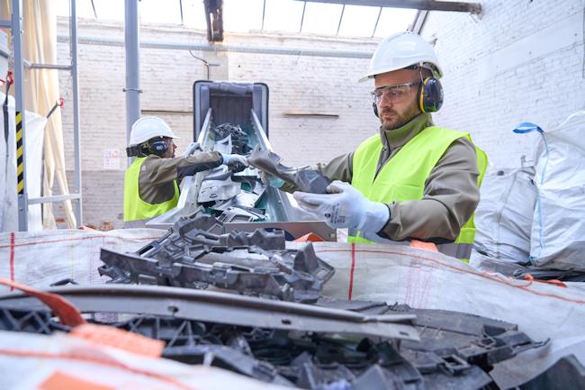 Workers sorting plastics on a conveyor belt.