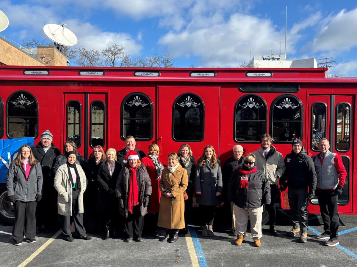 A group posed in front of a red trolley.