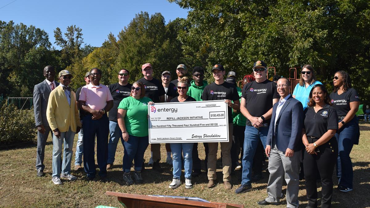 A group posed outside, some holding a large check.