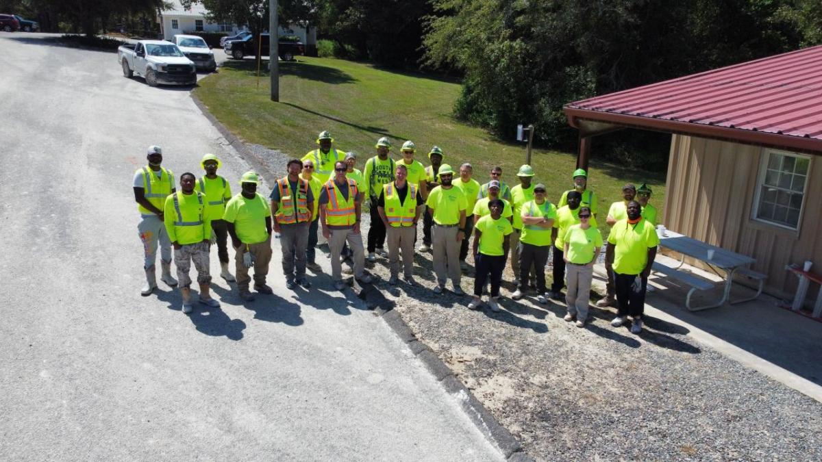 Group of employees posed outside in high-vis vests and hard hats.