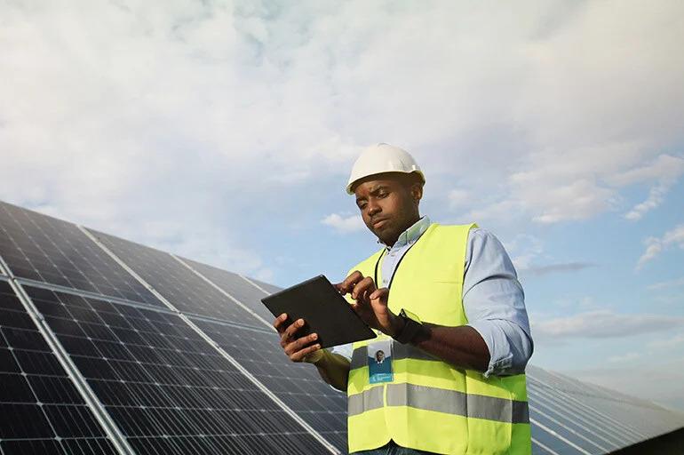 A person using a tablet next to solar panels.