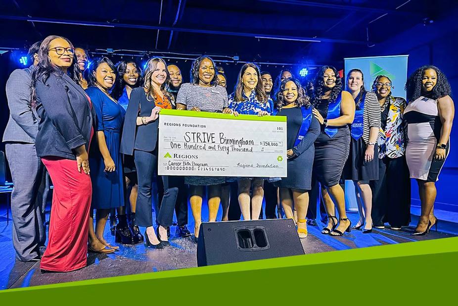 A group posed with a large check on a stage