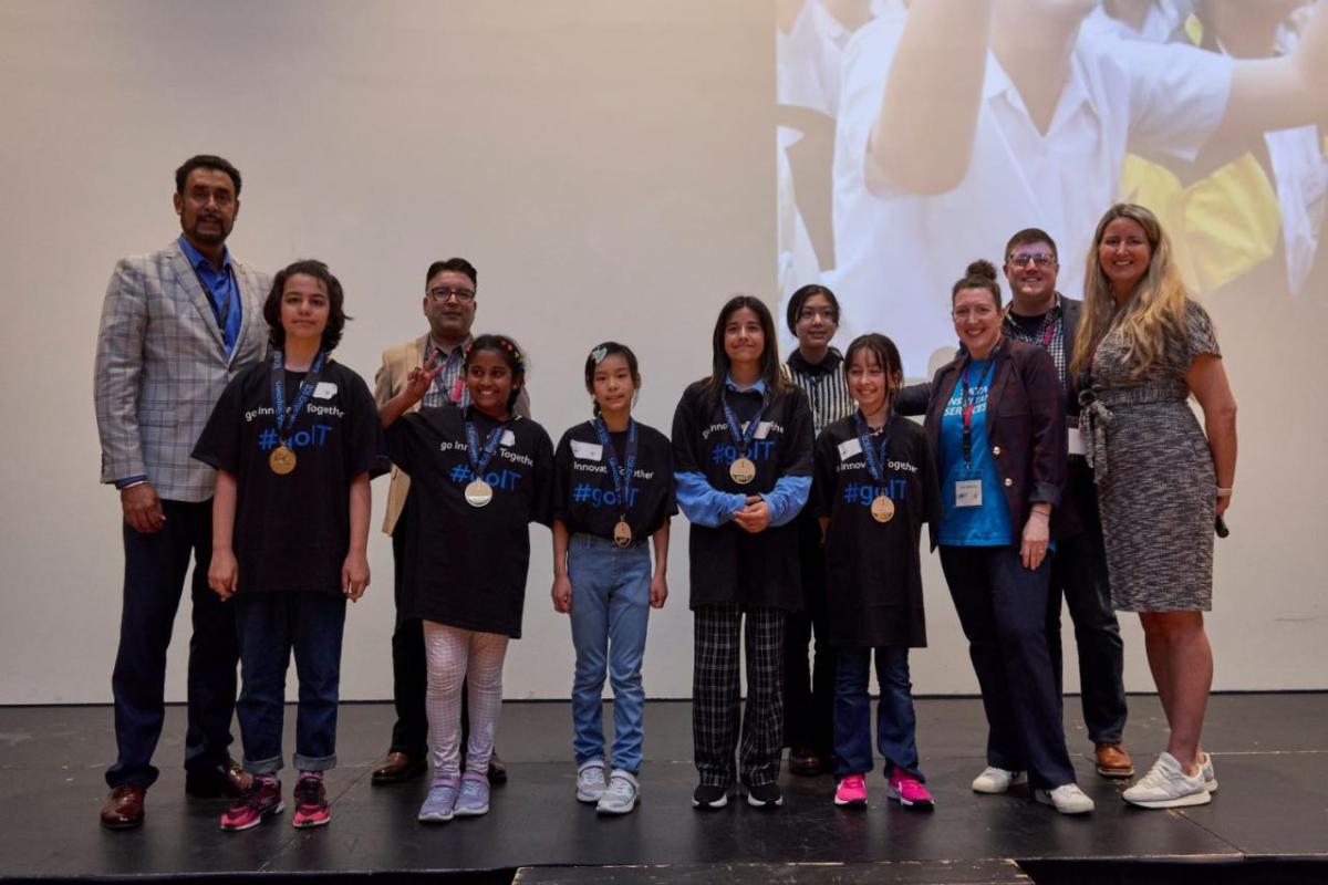 A group of students and presenters on a stage.