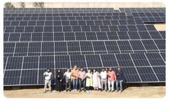 People posed in front of a field of solar panels.