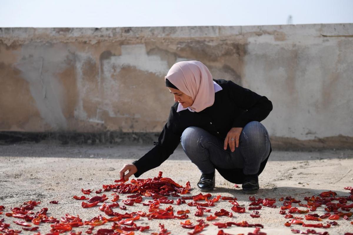 Lama*, 45, prepares tomato paste outside in Aleppo.