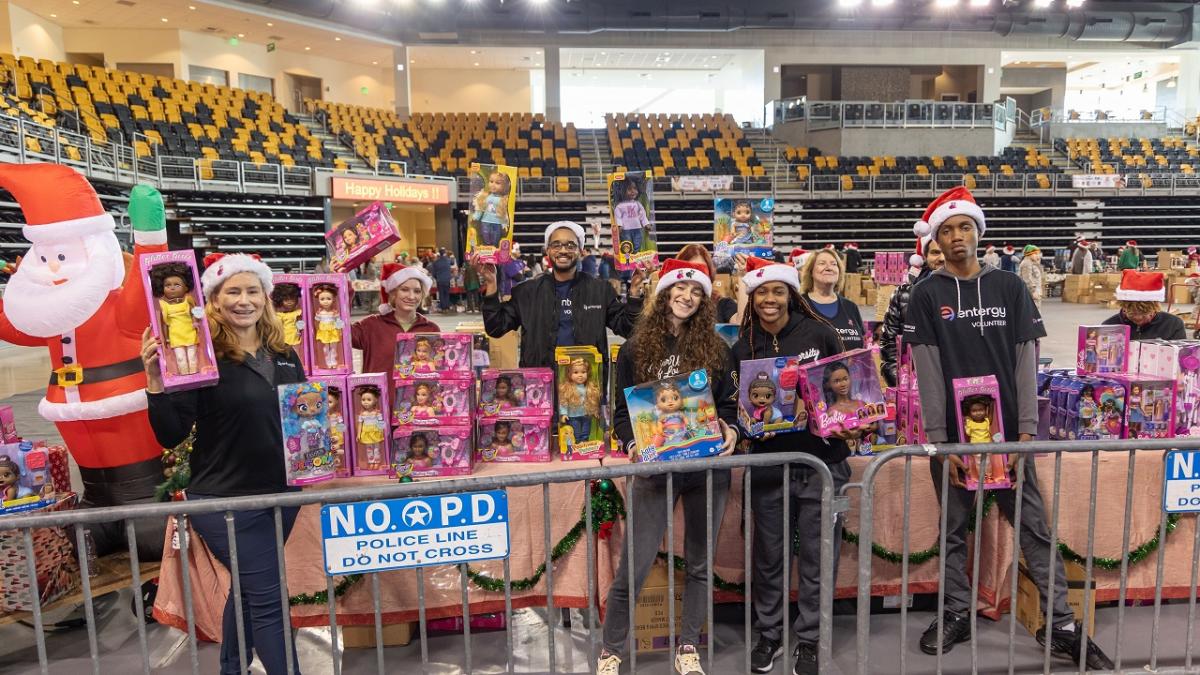 Volunteers holding up toys in a gymnasium.