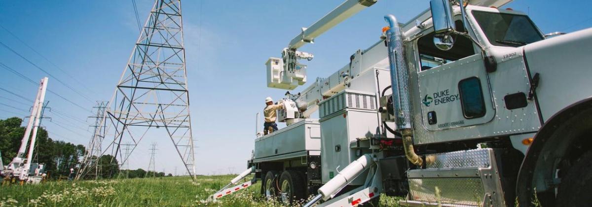 A power utility vehicle parked near tall power-line towers.