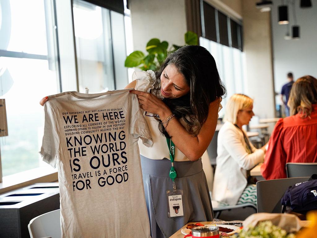 A person holding us a tshirt "...Knowing the world is ours..." and other writing on it.