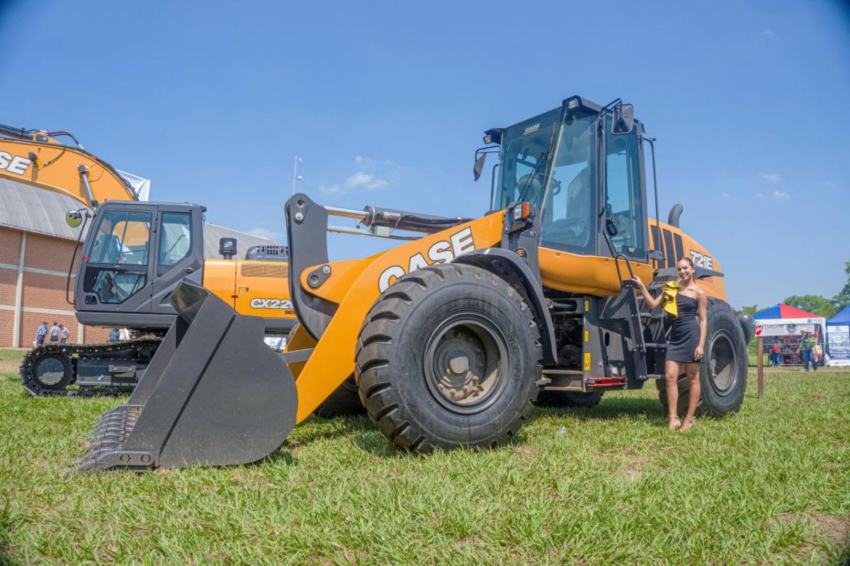 A person standing by a large bucket-style construction vehicle.